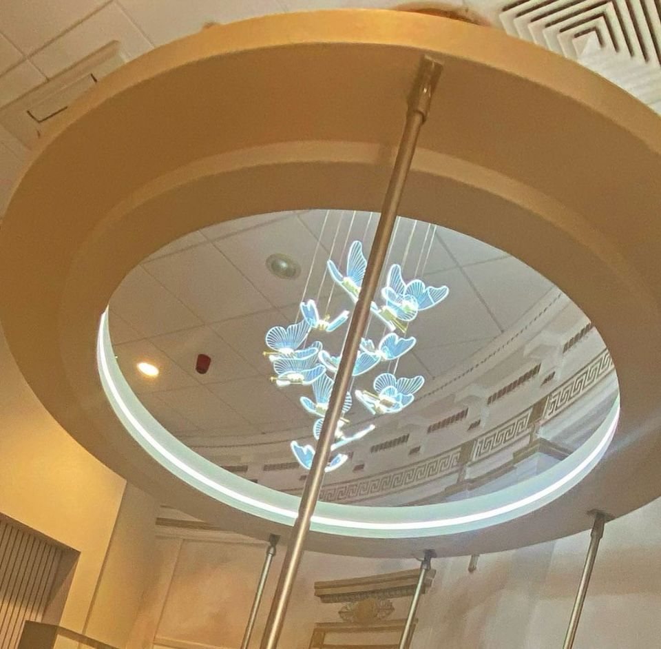 A chandelier of softly glowing blue butterflies hanging in a round ceiling opening